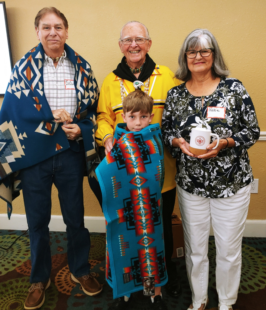 Three Tribal members of a variety of ages stand with Legislator Bob Whistler holding the gifts he gave them at a district meeting.