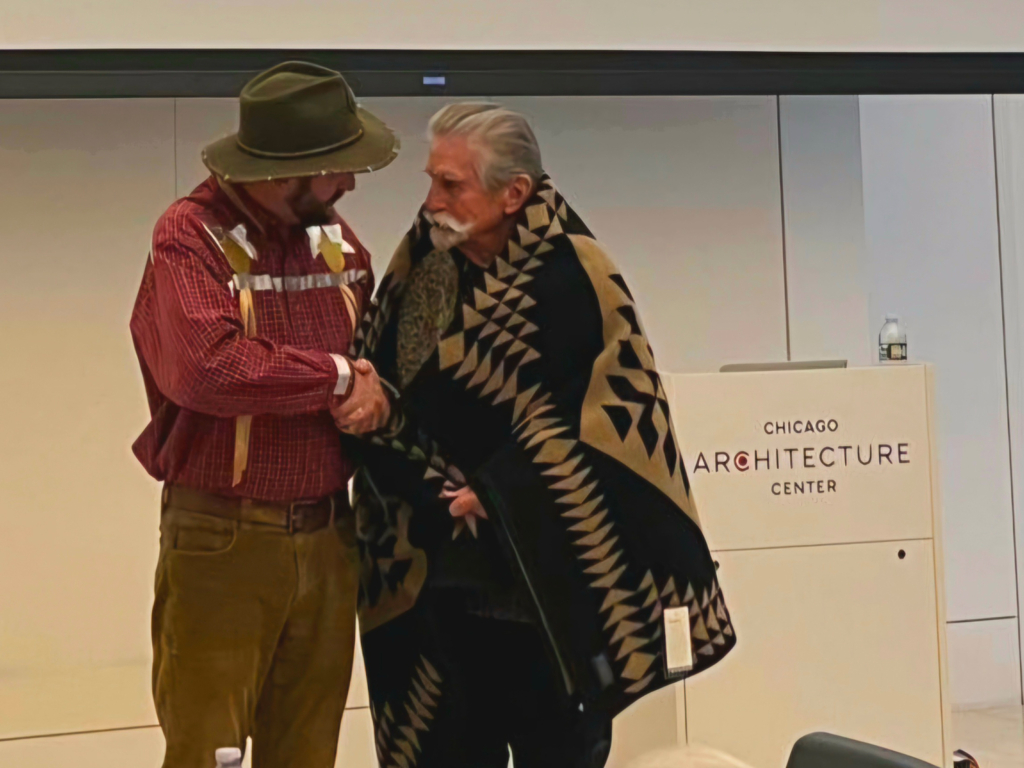 District 1 Legislator Alan Melot shakes hands with a Tribal member wrapped in a Pendleton blanket.