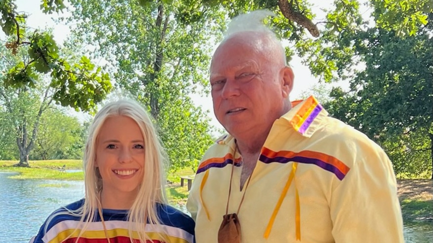 Kaylee Almand, in blue regalia with ribbons in the colors of the four directions, stands next to her grandfather, District 11 Legislator Andy Walters at the 2022 CPN Family Reunion Festival.