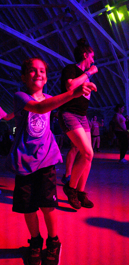 A child wearing a shirt with the CPN seal on it moves under blue and pink lighting. 